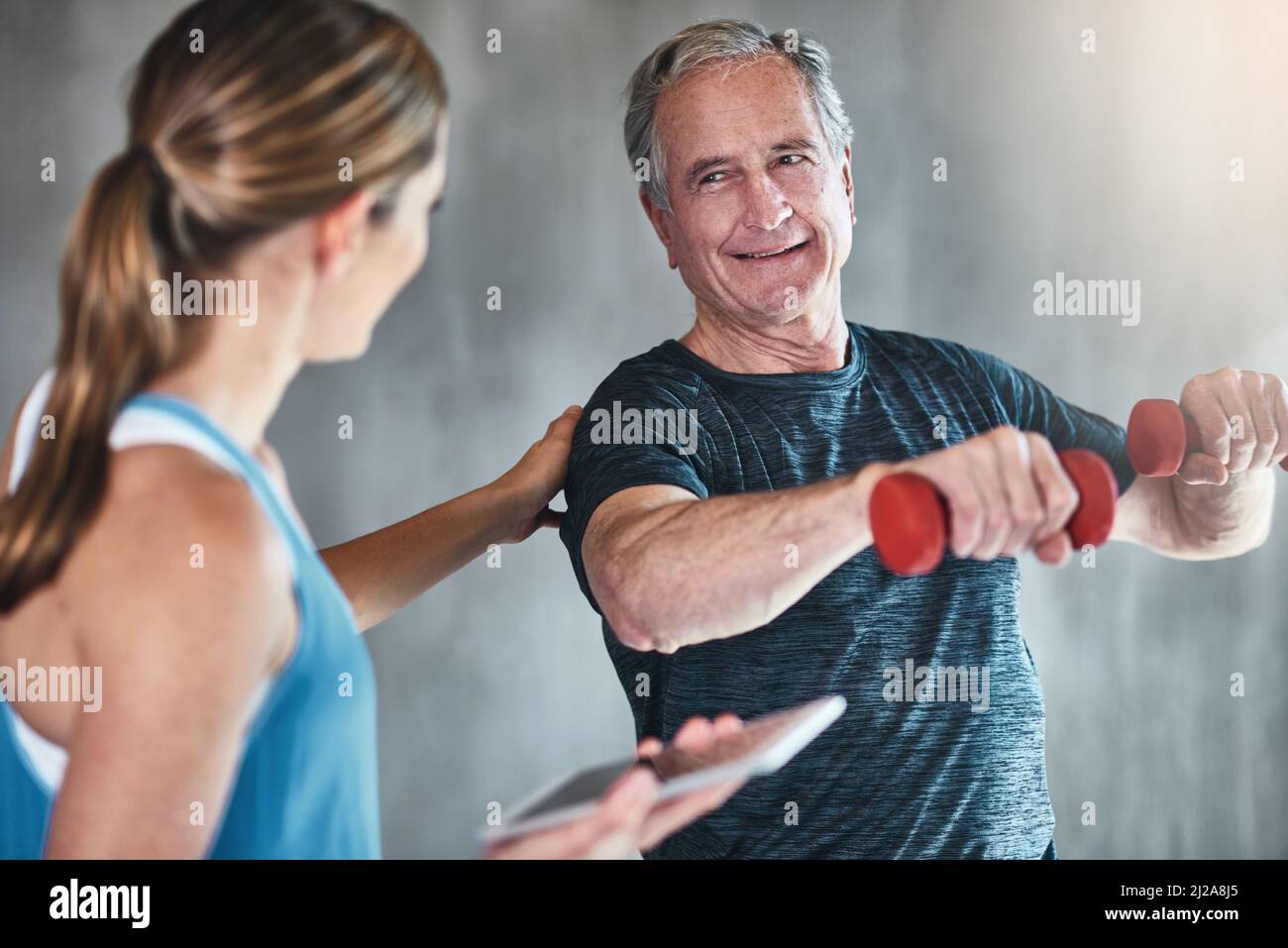 Älter werden, fitter werden, stärker werden. Aufnahme eines älteren Mannes mit Gewichten mit Hilfe eines Physiotherapeuten. Stockfoto