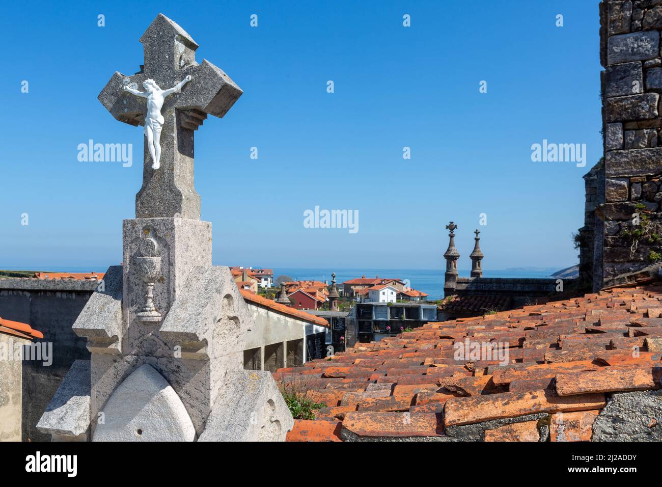 Nahaufnahme eines Steinkreuzes mit Figur von jesus christus auf dem Friedhof mit Meerblick Stockfoto