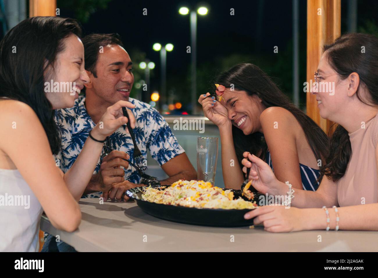 Eine Gruppe von Freunden, die in einem Restaurant Fast Food essen. Fröhliche junge Menschen essen und genießen sich in einem Fast-Food-Restaurant. Stockfoto