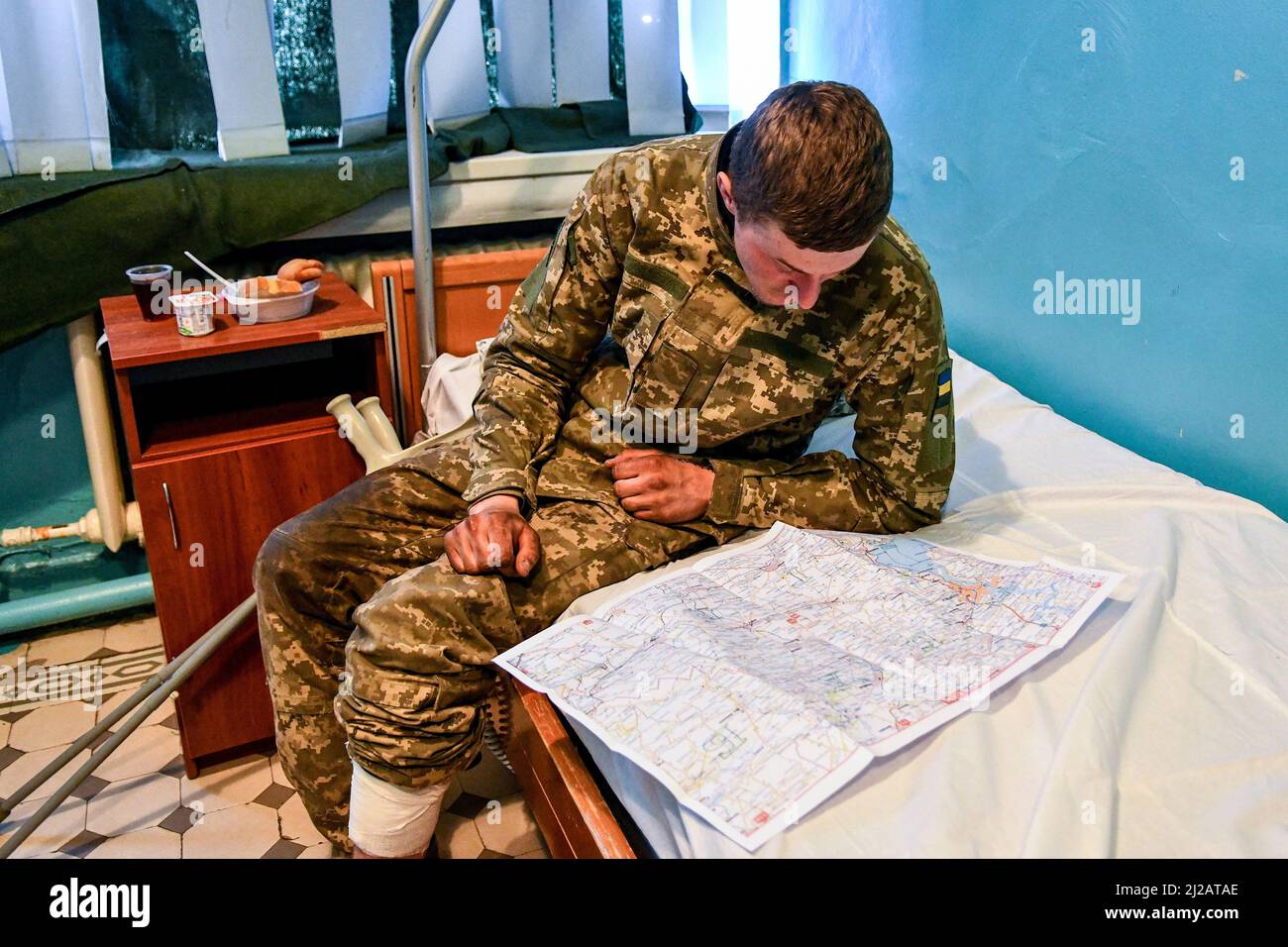 ZAPORIZHZHIA, UKRAINE - 29. MÄRZ 2022 - Soldat Andrii, 19, der aus seinem Bein ein Schrapnellstück herausnehmen ließ, studiert eine Karte eines Ortes, an dem er sich anschrecke Stockfoto
