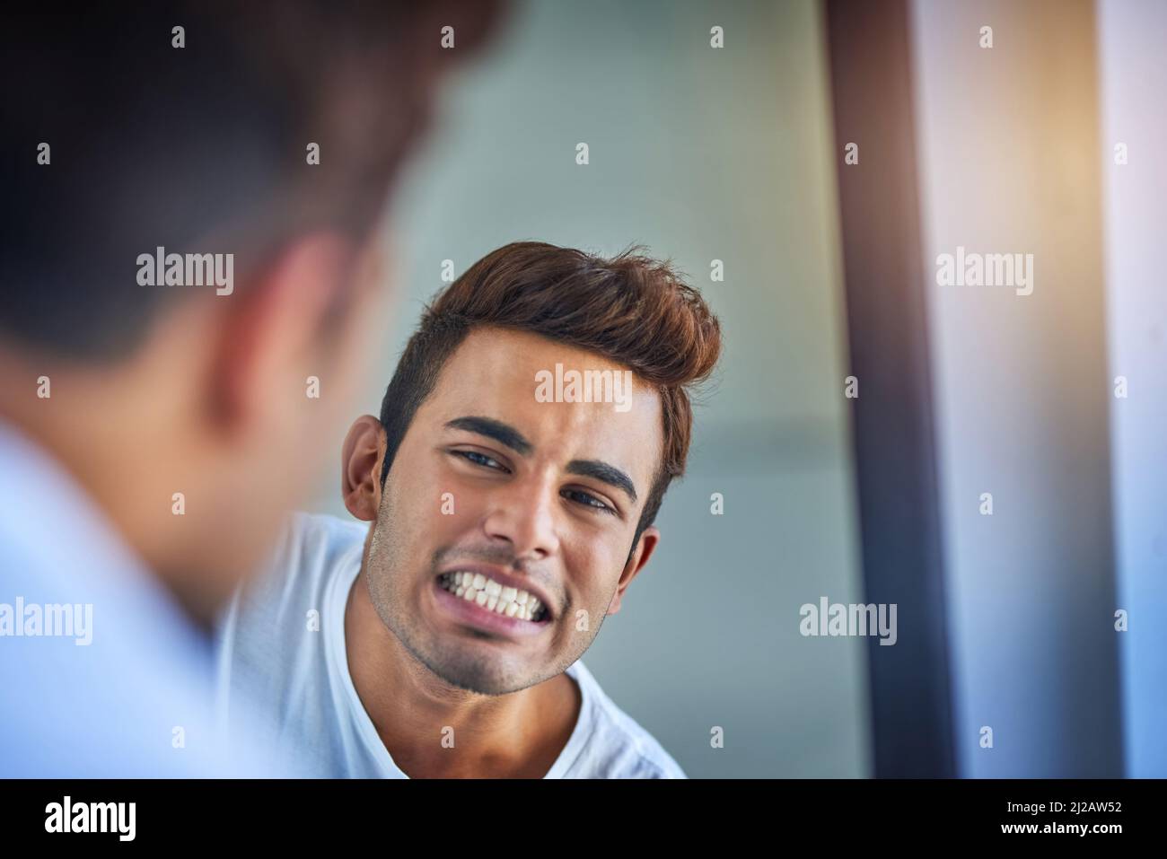 Zähne in neuwertigem Zustand. Aufnahme eines hübschen jungen Mannes, der seine frisch gebürsteten Zähne im Badezimmerspiegel bewundert. Stockfoto
