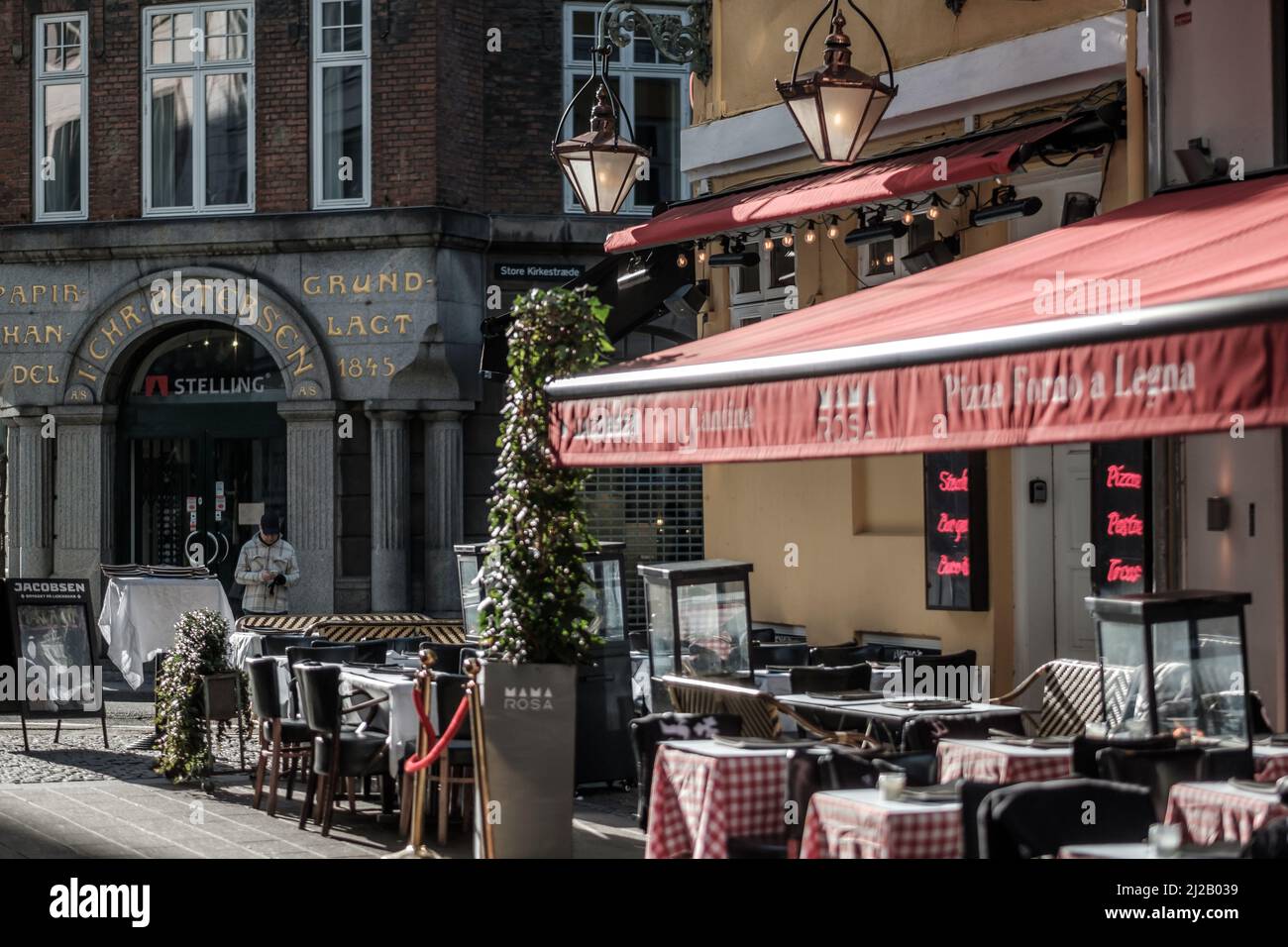 Ein italienisches Restaurant im alten Kopenhagen, das an einem sonnigen späten Wintertag seine Terrasse aufbaut. Stockfoto