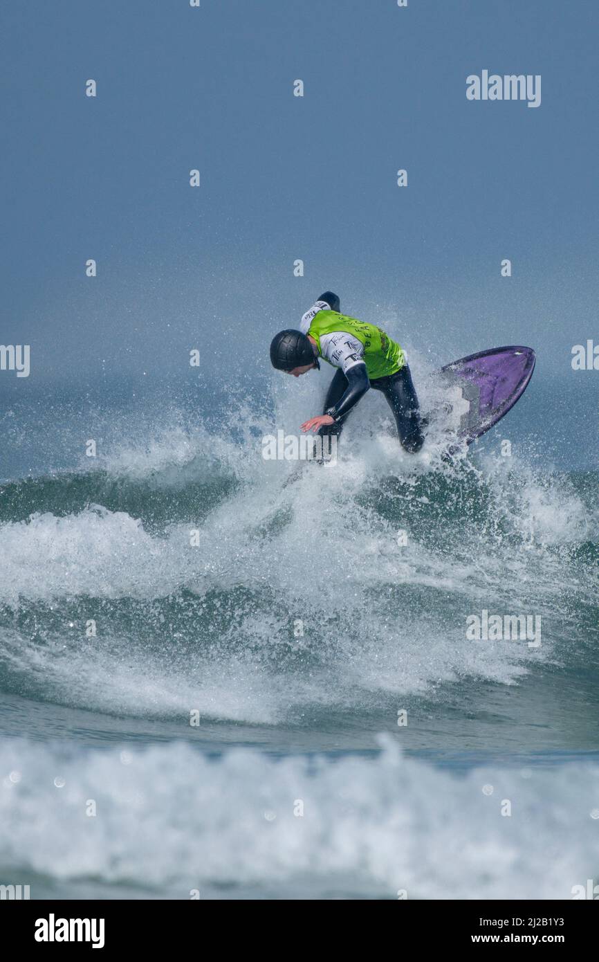 Ein männlicher Surfer, der an einem Surfwettbewerb im britischen Fistral in Newquay in Cornwall teilhat. Stockfoto