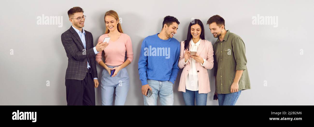 Gruppe von glücklichen jungen Männern und Frauen mit ihren modernen Handys und Spaß haben Stockfoto