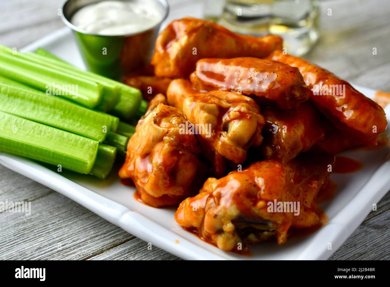 Buffalo Wings mit Sellerie-Sticks und Ranchverband auf einem weißen rechteckigen Teller Stockfoto