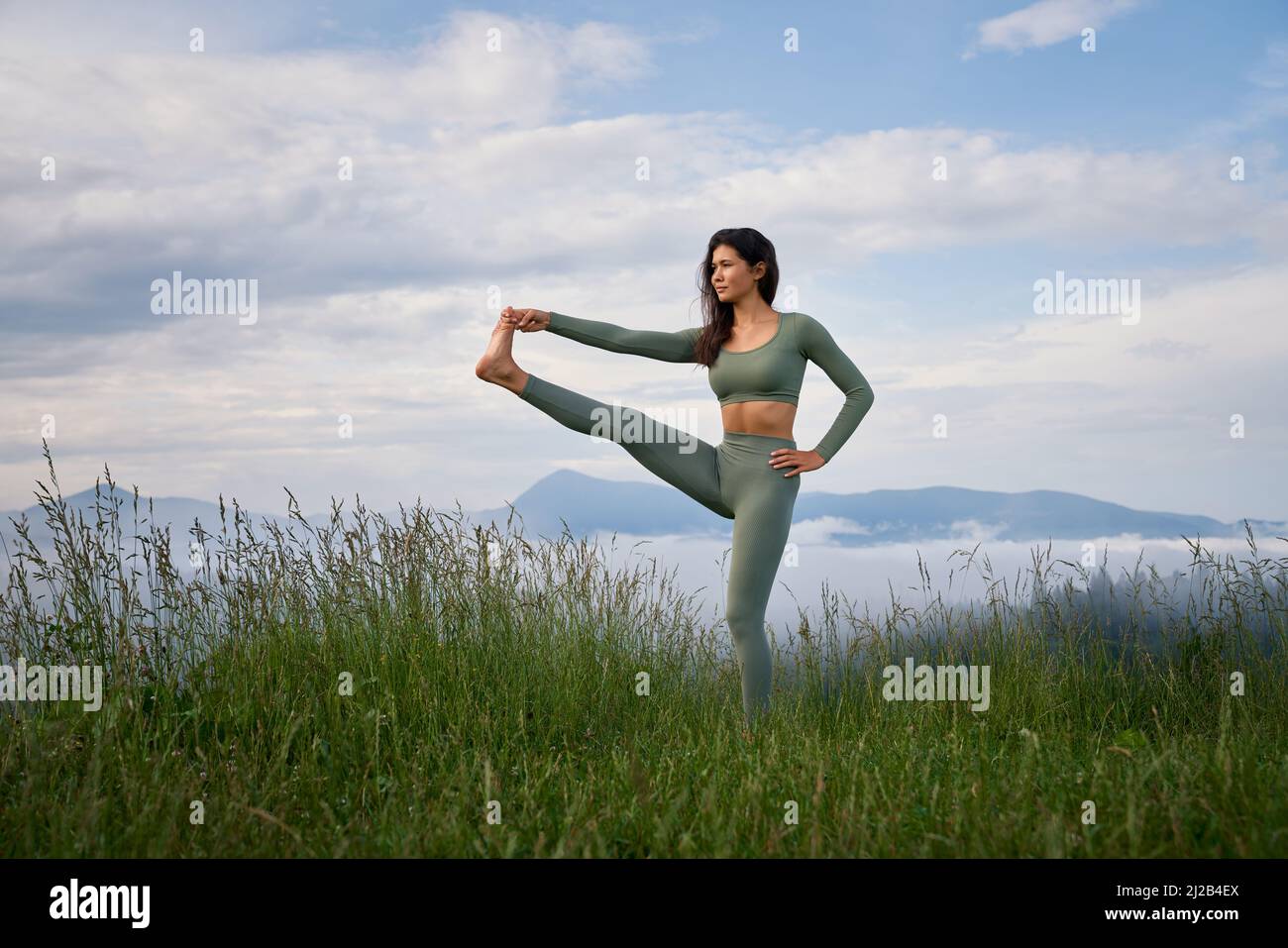 Junge sportliche Frau mit aktivem Outfit, die im Stretching-Training in den Sommerbergen trainiert. Morgens Zeit für aktives Training. Gesunde Lebensweise. Stockfoto
