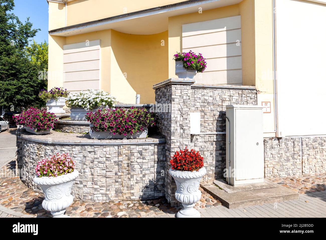 Dekorative Blumen an der Stadtstraße im Sommer sonnigen Tag. Städtische Floristik im Sommer. Große Blumentöpfe mit verschiedenen dekorativen Blumen Stockfoto