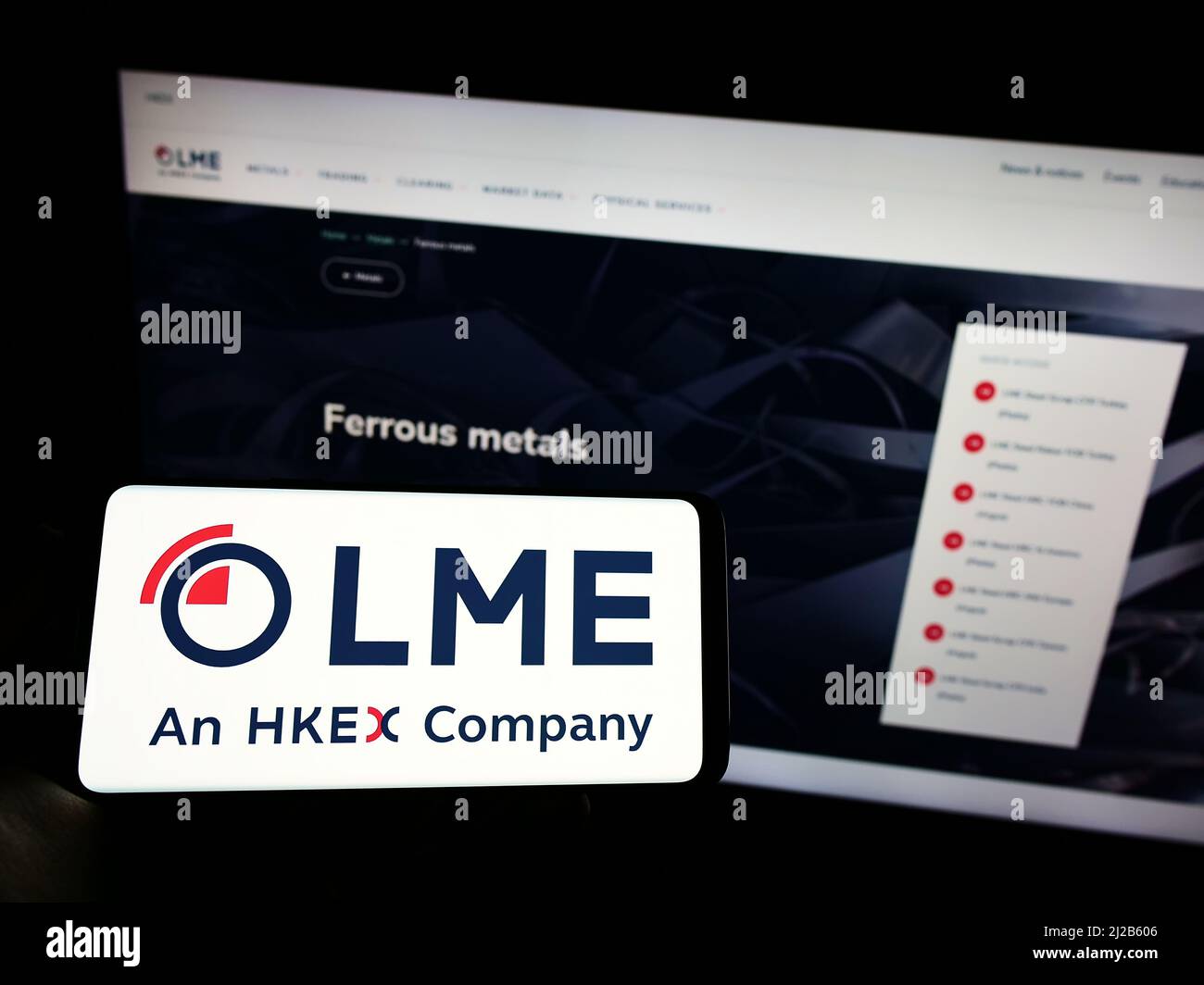 Person mit Mobiltelefon und Logo der britischen Börse London Metal Exchange (LME) auf dem Bildschirm vor der Business-Webseite. Konzentrieren Sie sich auf die Telefonanzeige. Stockfoto
