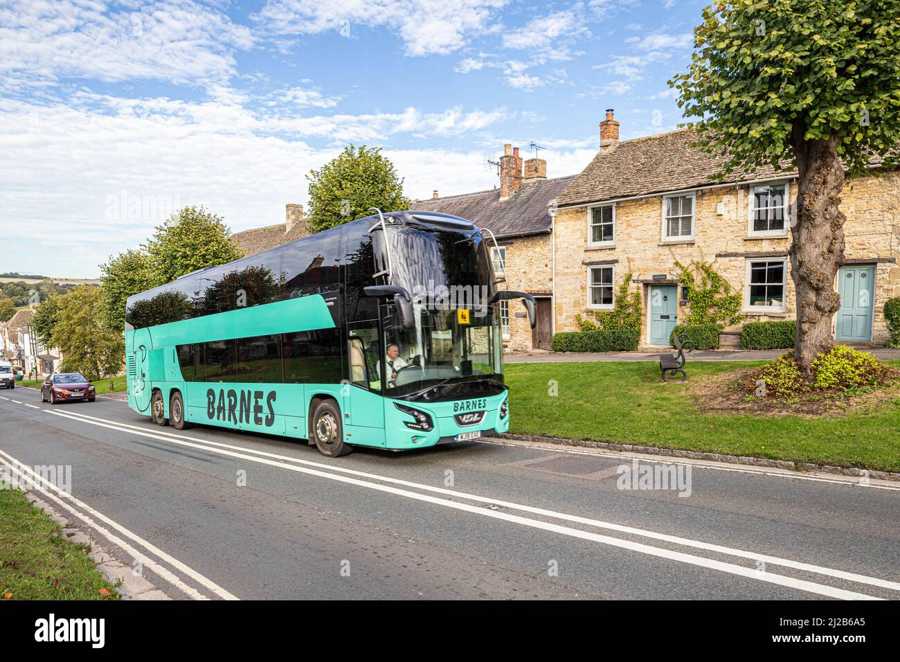 Ein Urlaubs- oder Tagesausflug mit dem Reisebus, der den Hügel in der Cotswold-Stadt Burford, Oxfordshire, England, hinauf fährt Stockfoto