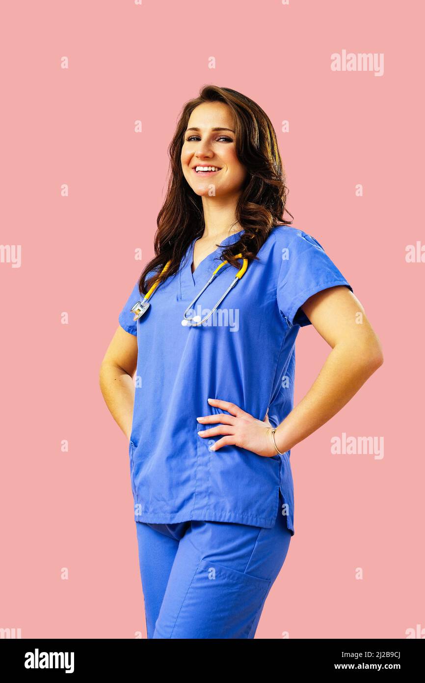Porträt einer lächelnden Ärztin oder Krankenschwester, die in blauer Uniform posiert und die Hände an der Taille hält Stockfoto