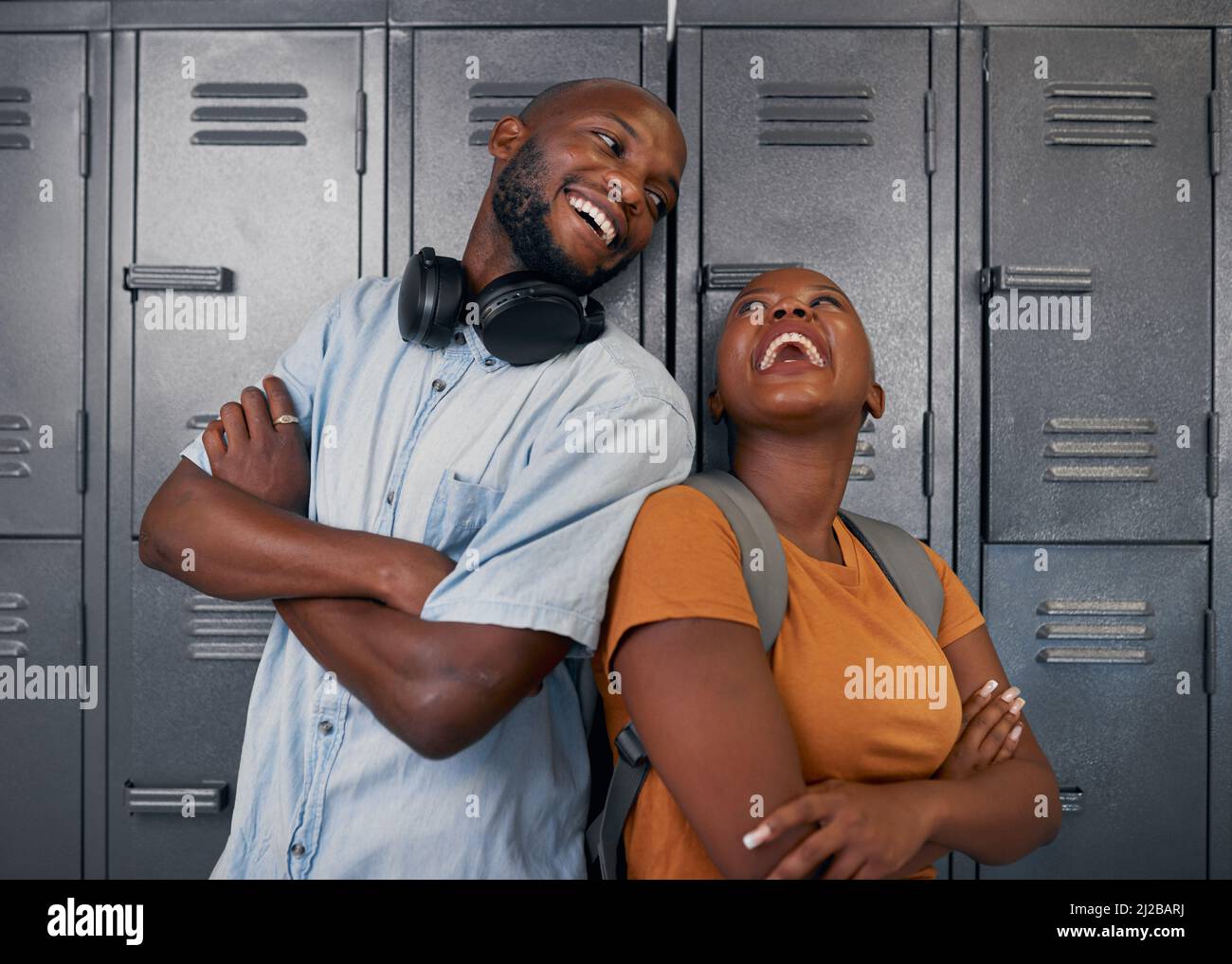 Zwei junge schwarze Studenten lachen und posieren vor den Schließfächern des Campus in der Schule Stockfoto