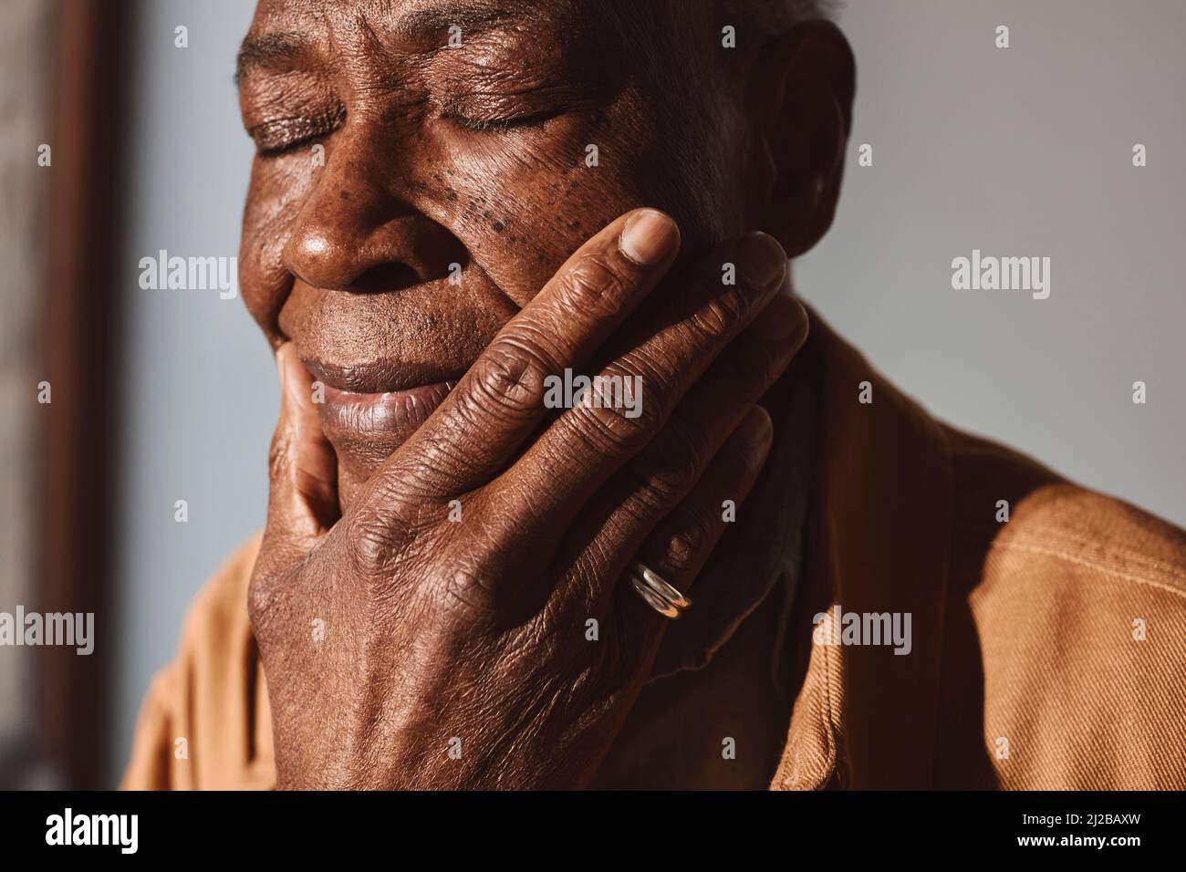 Älterer Mann mit der Hand am Kinn an der Wand Stockfoto