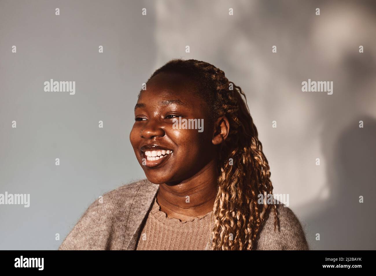 Glückliche Frau, die vor weißem Hintergrund wegschaut Stockfoto