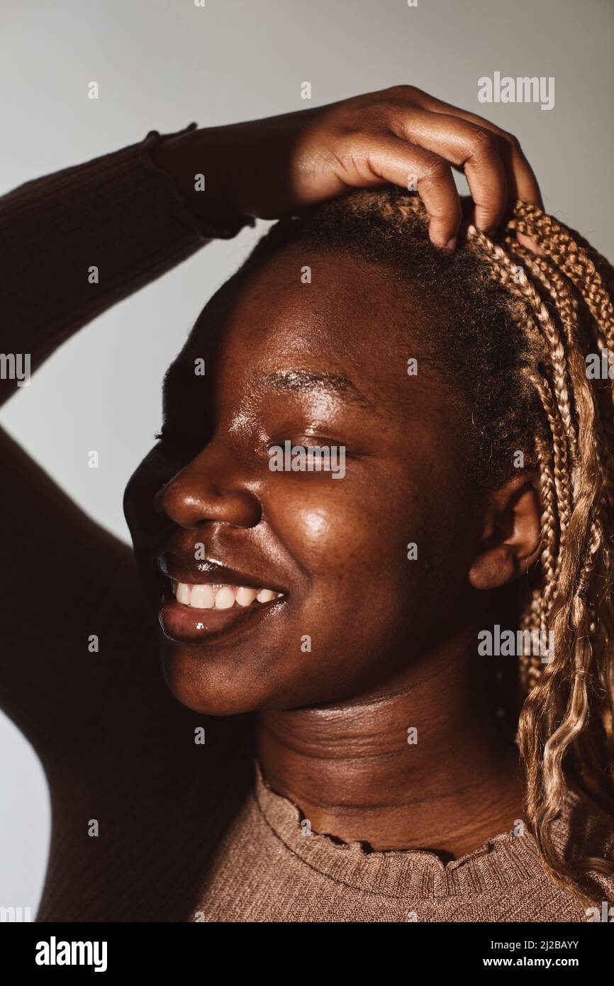 Lächelnde Frau mit der Hand im Haar im Studio Stockfoto