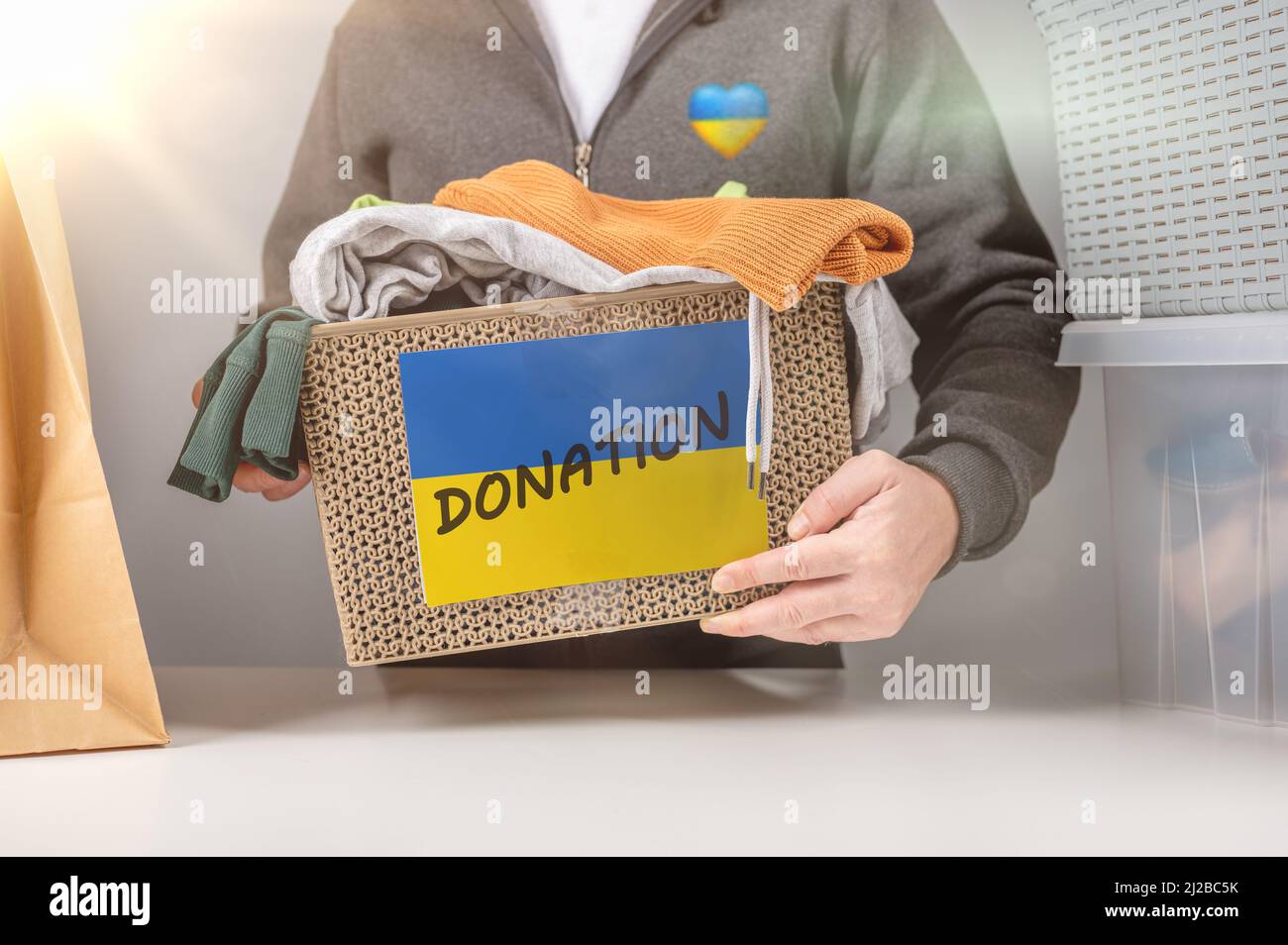 Spenden für Flüchtlinge aus der Ukraine. Nahaufnahme der freiwilligen Zyrierkiste mit humanitärer Hilfe für ukrainische Flüchtlinge. Spendenbekleidung für Flüchtlinge f Stockfoto