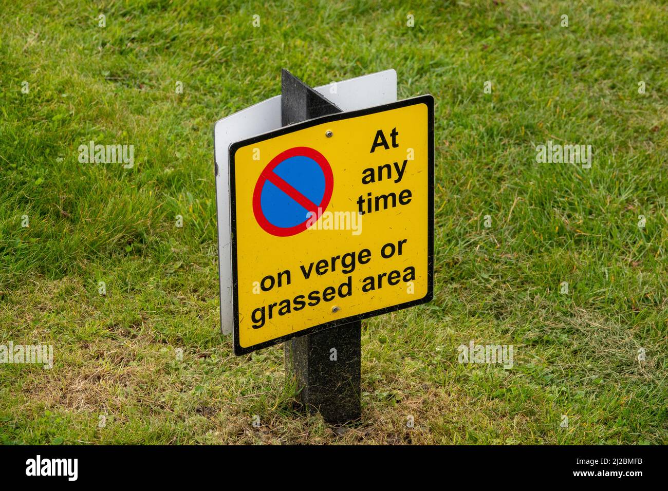 Kein Parkplatz am Rande oder auf dem Rasenschild an der kurzen Holzpfosten Stockfoto