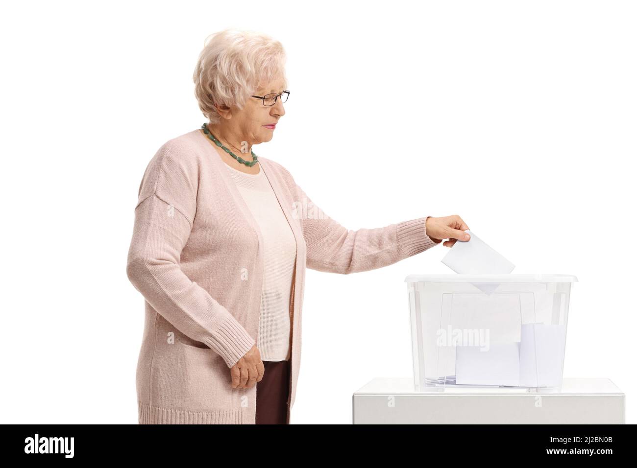 Ältere Frau, die in einer auf weißem Hintergrund isolierten Wahlurne ihre Stimme abgegeben hat Stockfoto