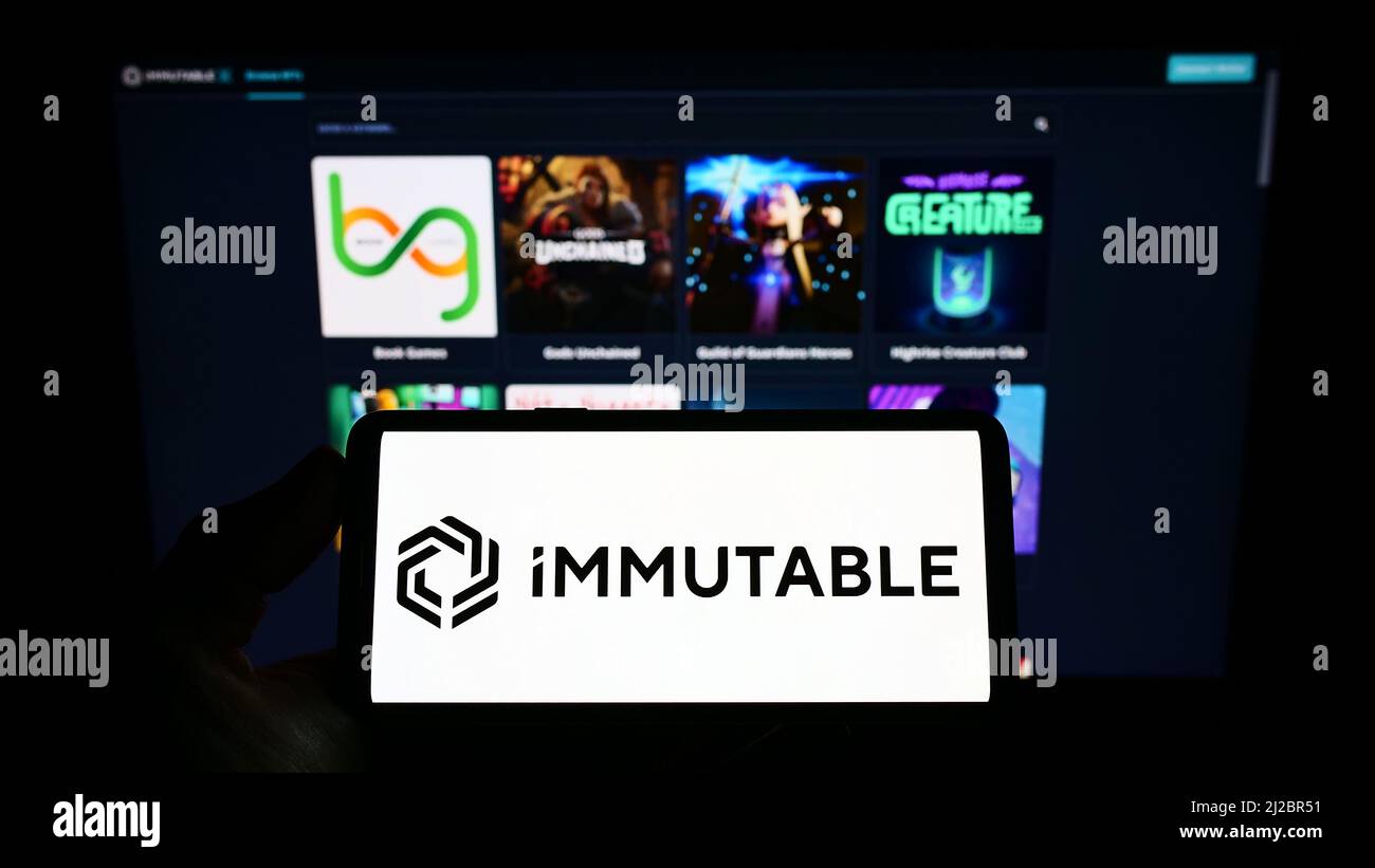 Person, die ein Mobiltelefon mit dem Logo der australischen Blockchain-Firma Immutable Pty. Ltd. Auf dem Bildschirm vor der Webseite hält. Konzentrieren Sie sich auf die Telefonanzeige. Stockfoto