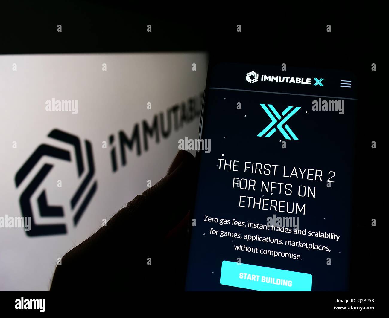 Person, die Mobiltelefon mit Website der australischen Blockchain-Firma Immutable Pty. Ltd. Auf dem Bildschirm mit Logo hält. Konzentrieren Sie sich auf die Mitte des Telefondisplays. Stockfoto