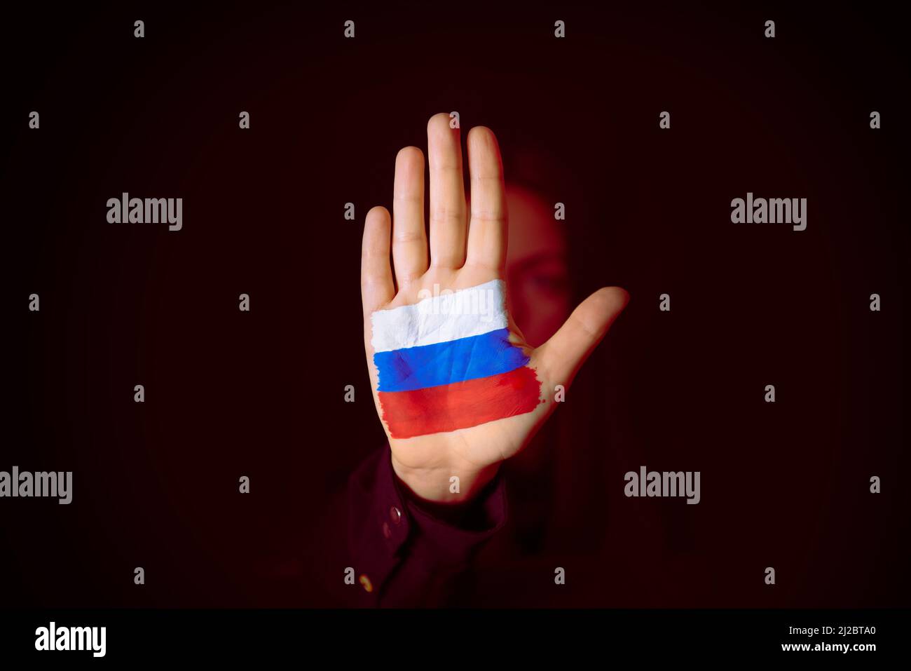Frau mit einer Stop-Geste zeigt russische Flagge in der Handfläche, stoppt den Krieg Stockfoto