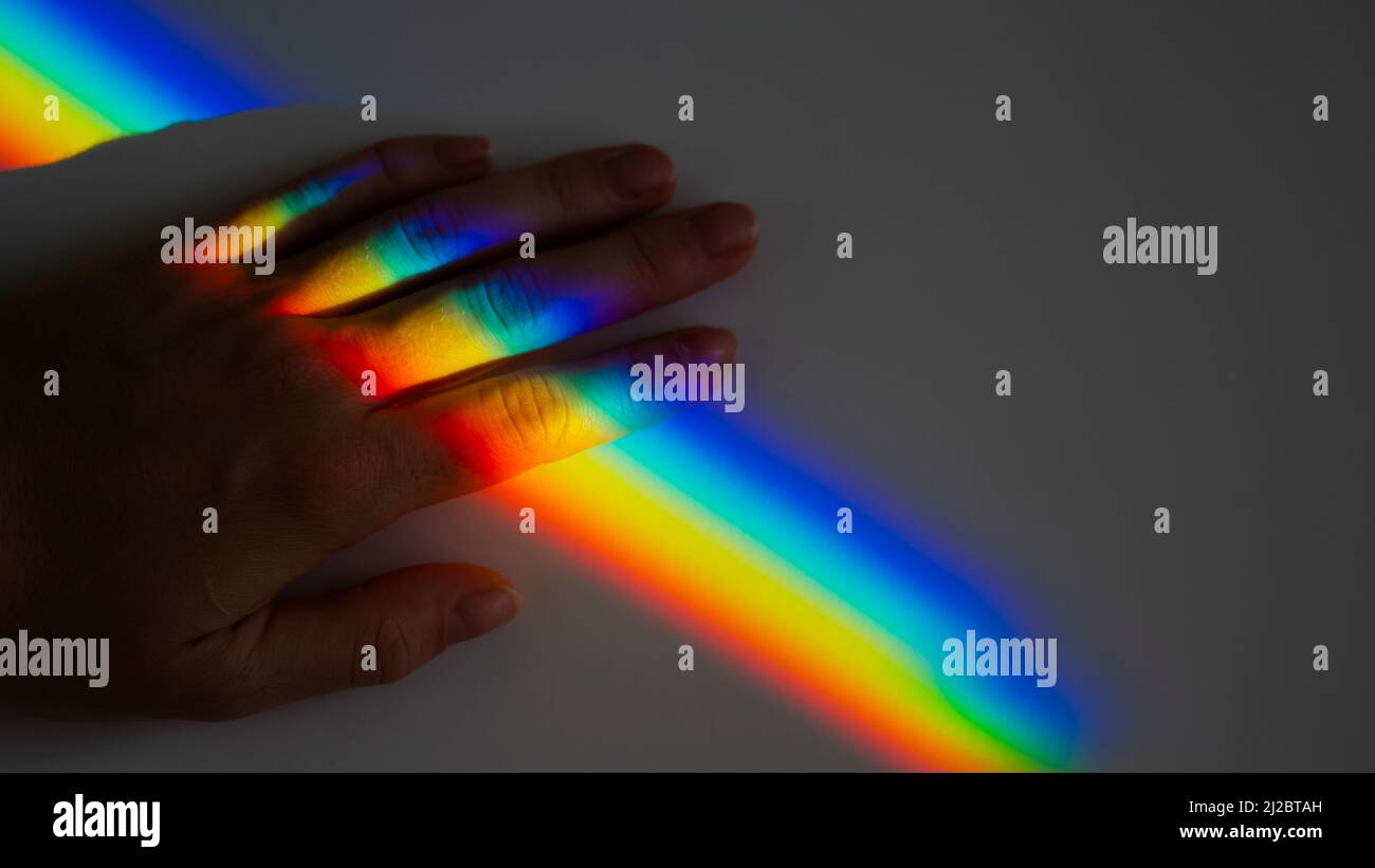 Regenbogenstrahl auf der Hand einer Frau. Stockfoto