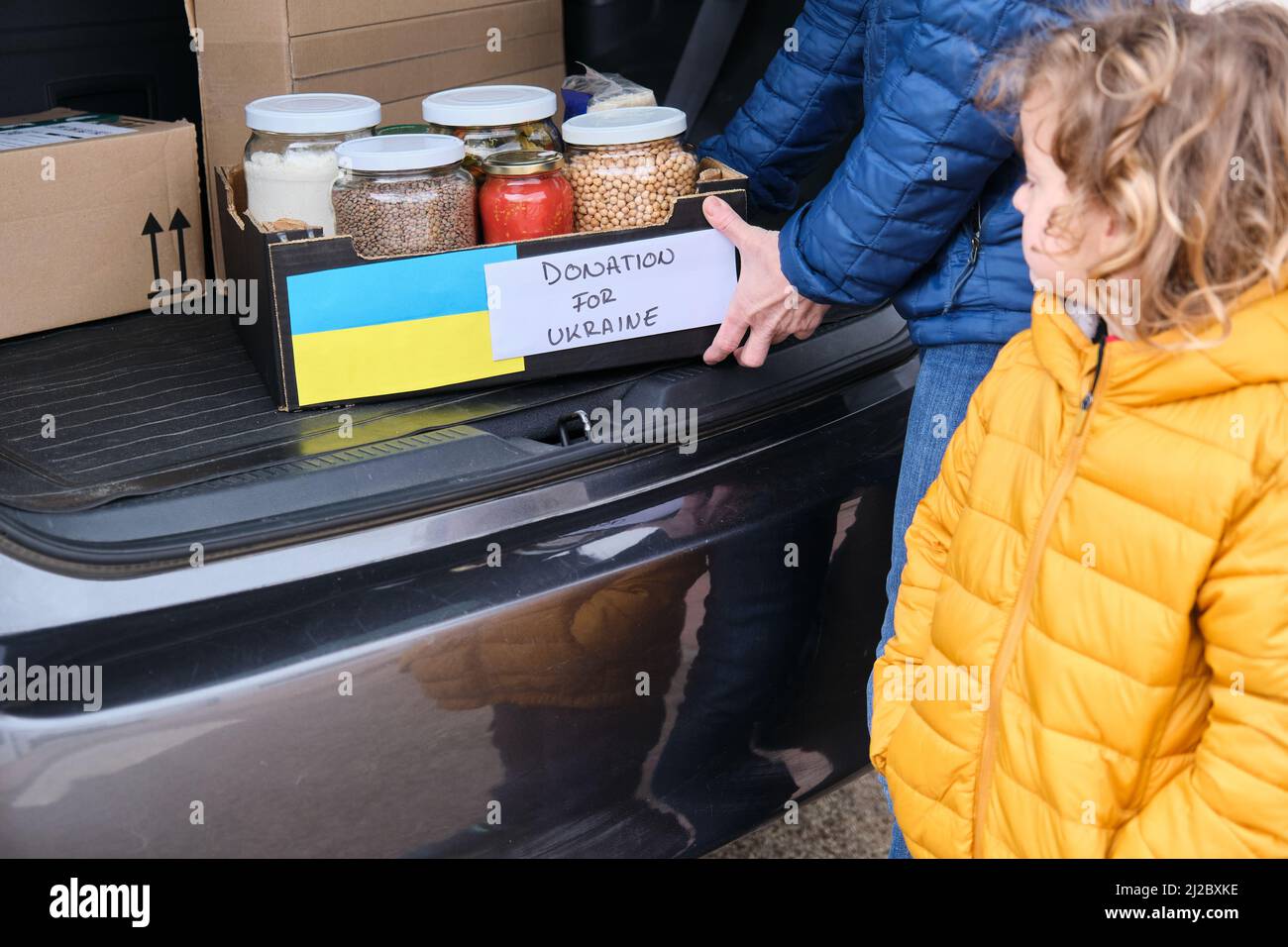 Mutter und Sohn, die eine Schachtel mit Lebensmitteln für ukrainische Flüchtlinge mitgenommen haben. Humanitäre Hilfe im Ukraine-Krieg Stockfoto