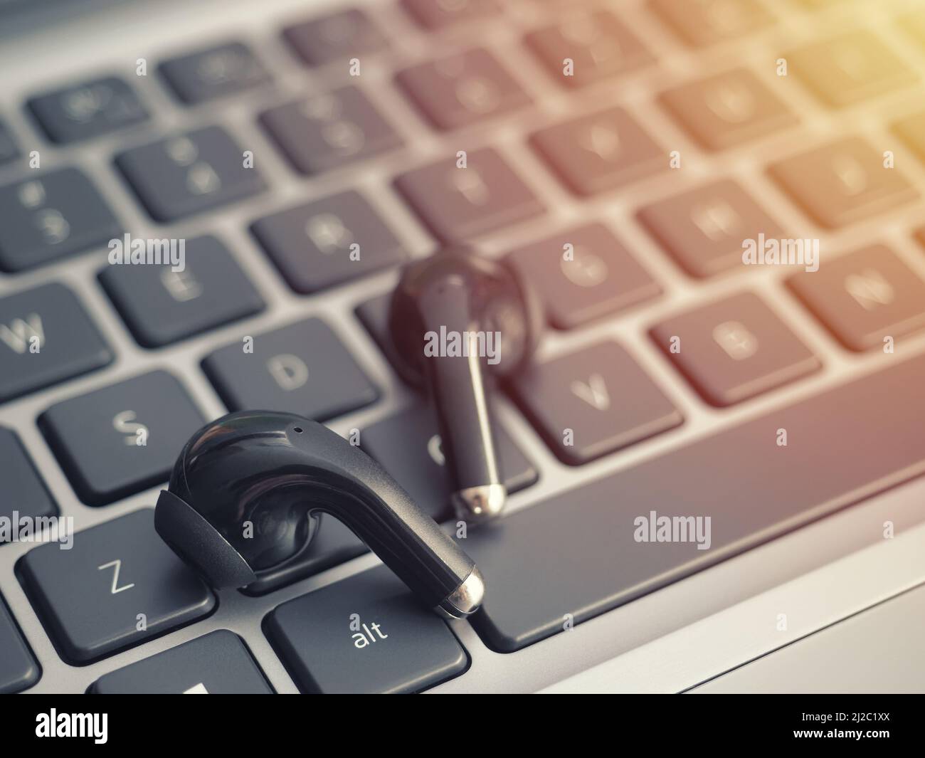 Kabellose Bluetooth-Kopfhörer auf einer Laptop-Tastatur. Mit Bluetooth ® True Wireless Headphones Filme ansehen und Musik auf einem Laptop hören Stockfoto