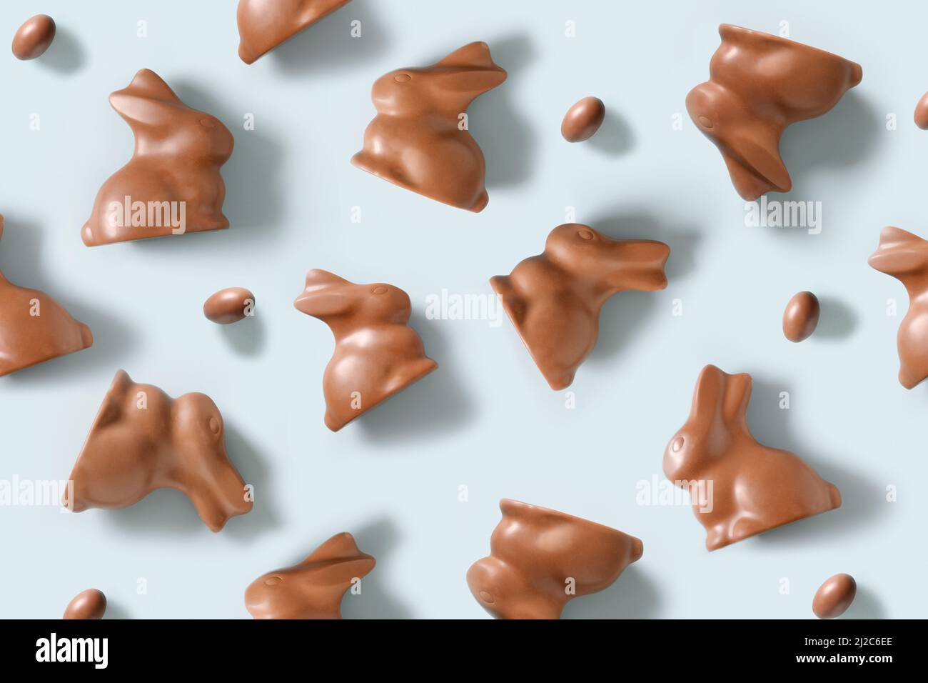 Ostermuster mit Schokoladenbonbons, Kaninchen oder Hasen und Eiern auf blauem Hintergrund. Flach liegend. Blick von oben. Stockfoto