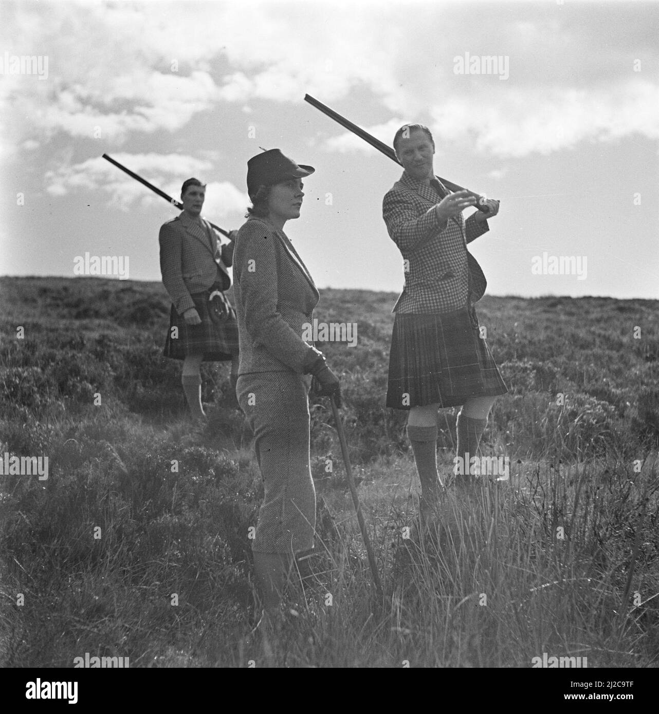 Frau mit einer Schrotflinte und zwei Männer im Kilt ca. 1930s-1950s Stockfoto