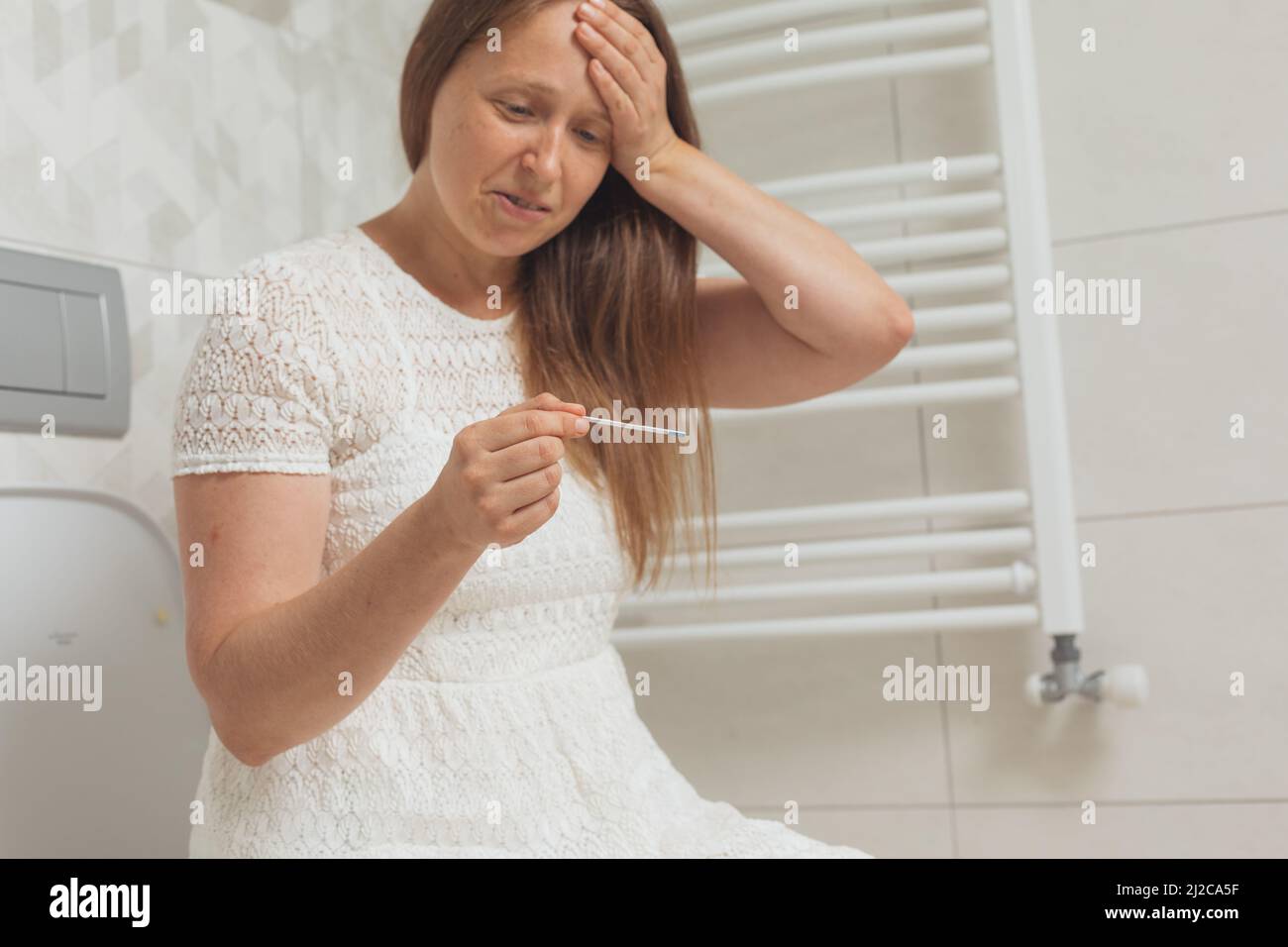 Verwirrt Frau mit Schwangerschaftstest in Toilette Stockfoto