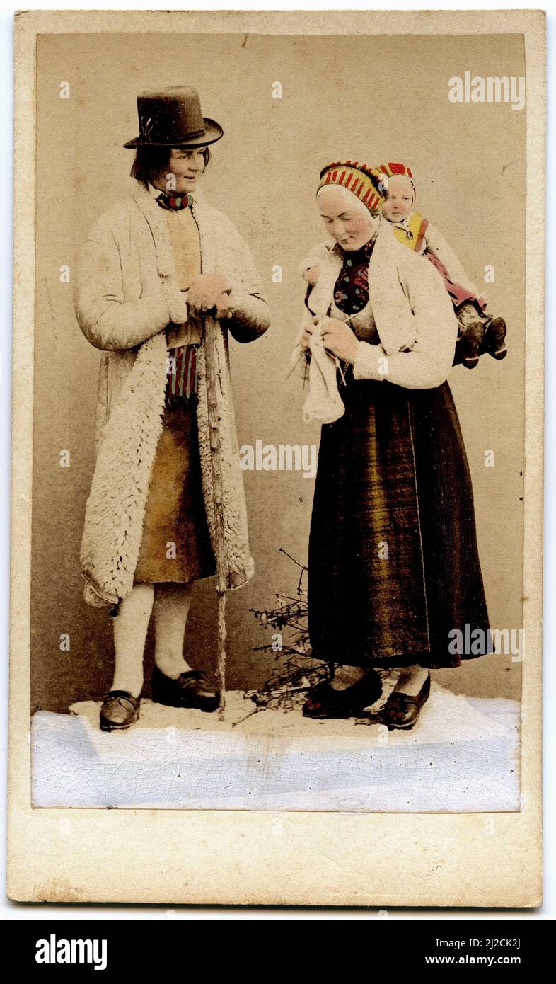 Koloriertes Foto einer Frau, die ein Baby auf dem Rücken trägt, und eines Mannes in traditioneller schwedischer Tracht, Dalarna, Schweden, um 1870. Fotografie von Eurenius & Quist. Stockfoto
