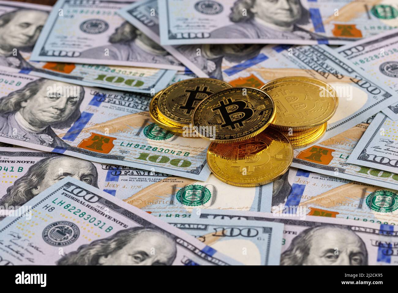 Kleiner Stapel gelber Bitcoin-Münzen, verstreut über US-Dollar-Papierbanknoten Stockfoto