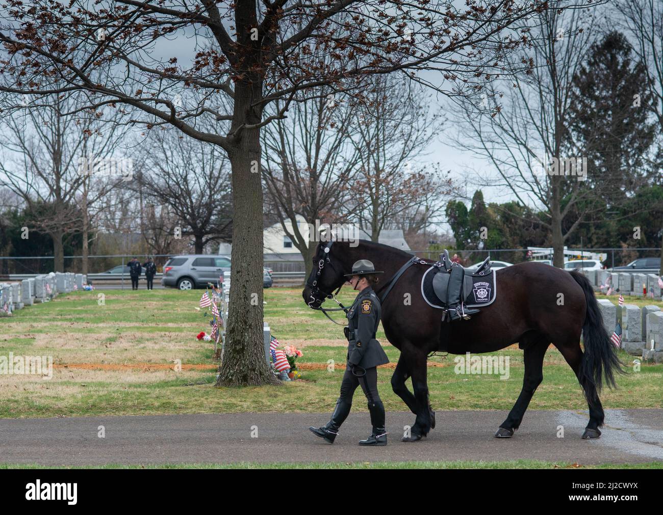 Langhorne, Usa. 31. März 2022. Ein Staatstruppler geht mit einem umnounted Pferd während der Interment-Dienste für Pennsylvania State Trooper Martin Mack III Donnerstag, 31. März 2022 auf dem Friedhof unserer Lady of Grace in Langhorne, Pennsylvania. Mack wurde letzte Woche im Dienst mit seinem Mitstreiter Brendan Sisca am I-95 getötet. Kredit: William Thomas Cain/Alamy Live Nachrichten Stockfoto