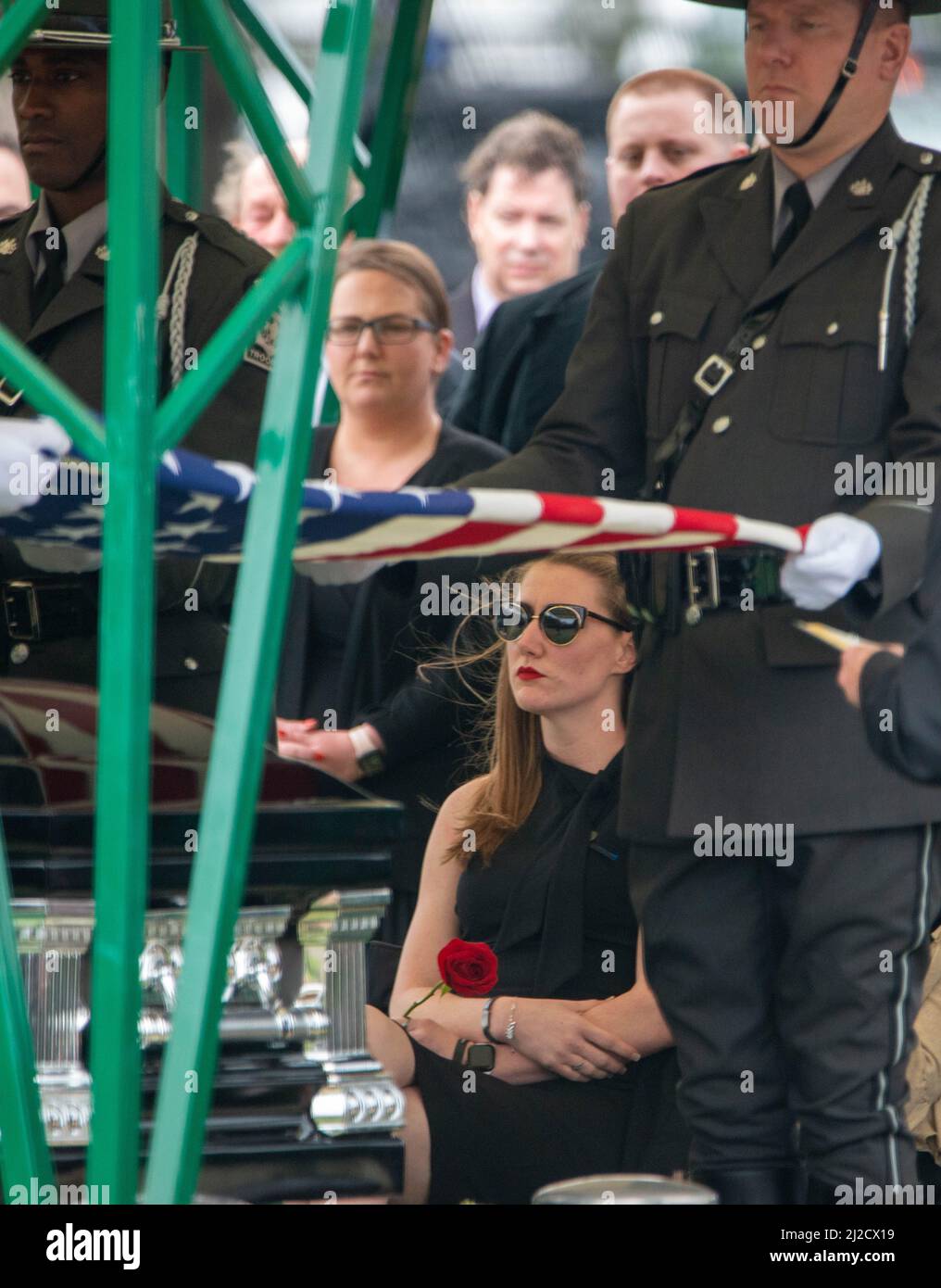 Langhorne, Usa. 31. März 2022. Stephanie Mack, Witwe des Pennsylvania State Trooper Martin Mack III, sieht an, wie eine amerikanische Flagge über die Schatulle ihres Ehemanns drapiert während der Interment-Dienste für ihn Donnerstag, 31. März 2022 auf dem Friedhof unserer Lieben Frau von Grace in Langhorne, Pennsylvania. Mack wurde letzte Woche im Dienst mit seinem Mitstreiter Brendan Sisca am I-95 getötet. Kredit: William Thomas Cain/Alamy Live Nachrichten Stockfoto