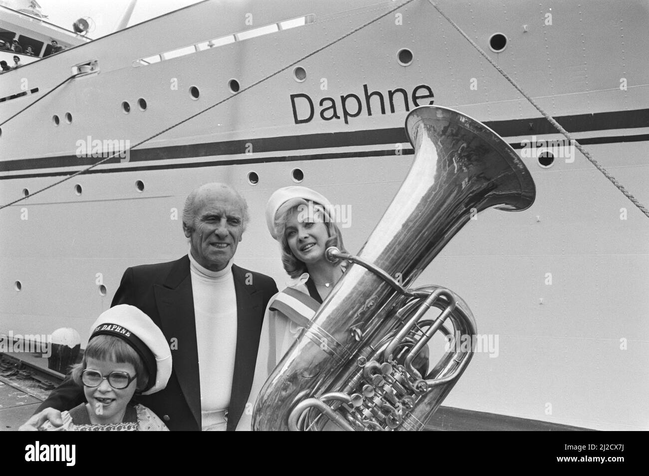 Griechisches Carras-Kreuzschiff Daphne in Amsterdam, Miss Holland (Nanny Nielen) mit Tuba und Schiffseigner Carras vor dem Schiff. Der Vorname des Mädchens vorne links ist ebenfalls Daphne Ca. 28 Mai 1976 Stockfoto