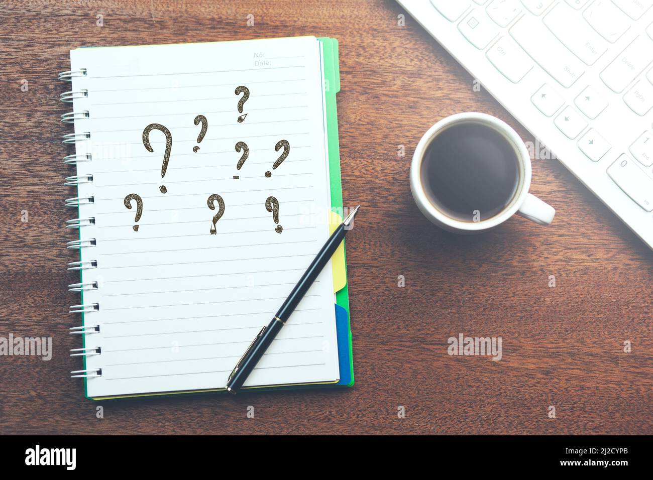 Fragezeichen auf Notizblock mit Tastatur und Kaffee auf dem Tisch Stockfoto