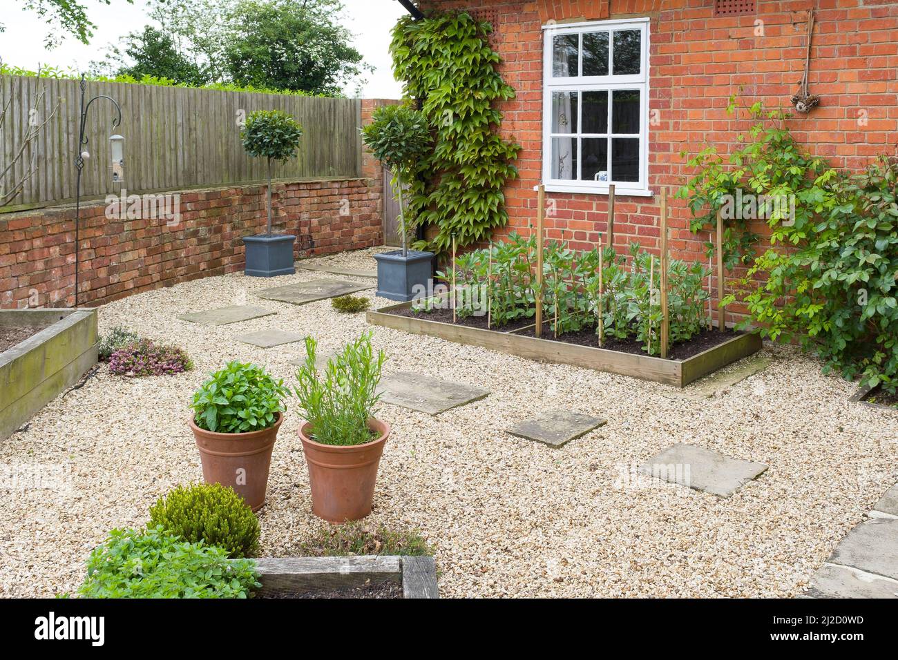 Garten hinten UK. Landschaftlich gestalteter Garten mit Kies, York Steintretsteinen und erhöhten Betten mit Eichenholzbett Stockfoto