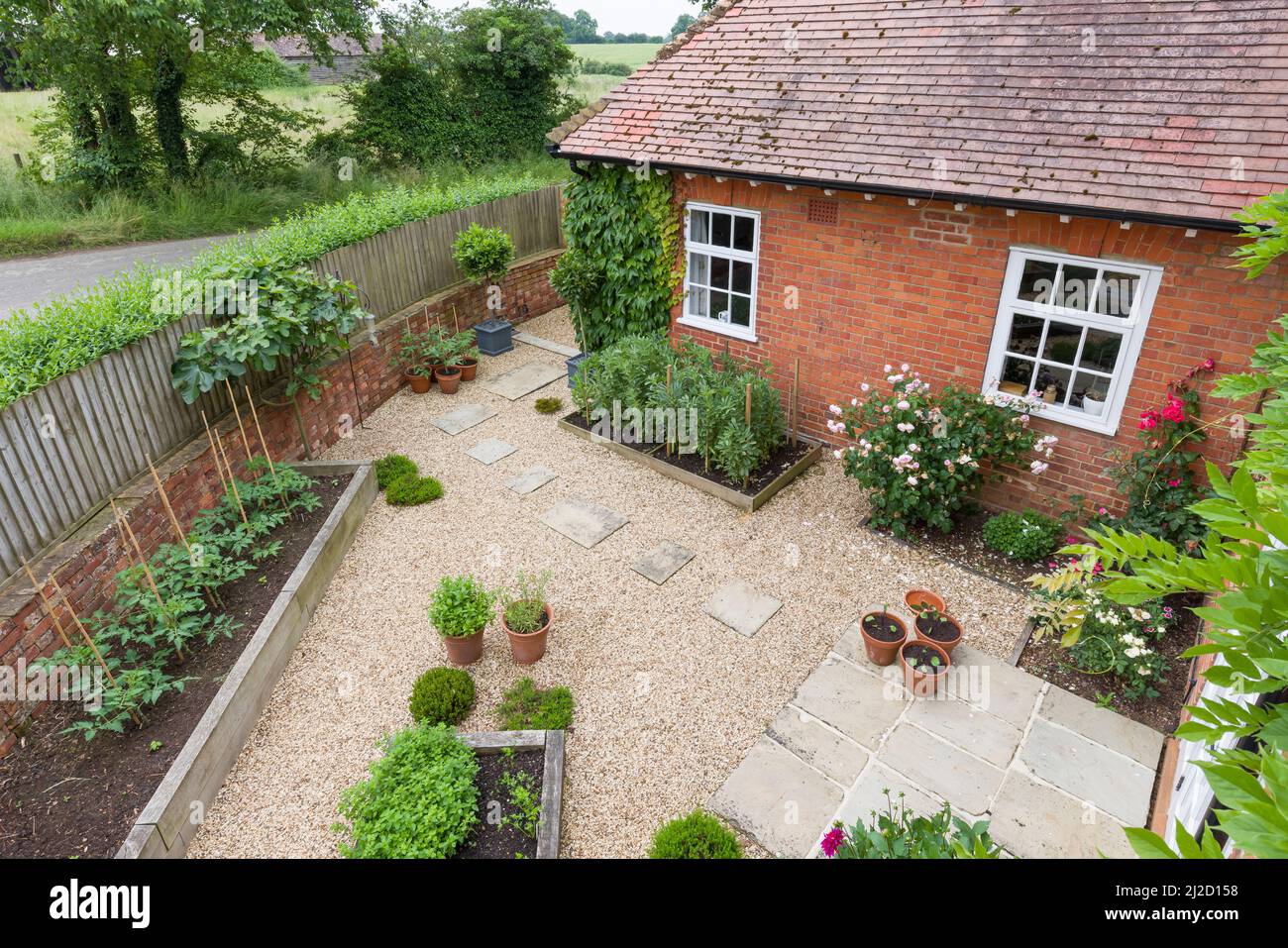 Gartenterrasse Großbritannien. Landschaftlich gestalteter Garten mit Kies, Hochbetten und York-Steinsteinen und Terrasse. Stockfoto