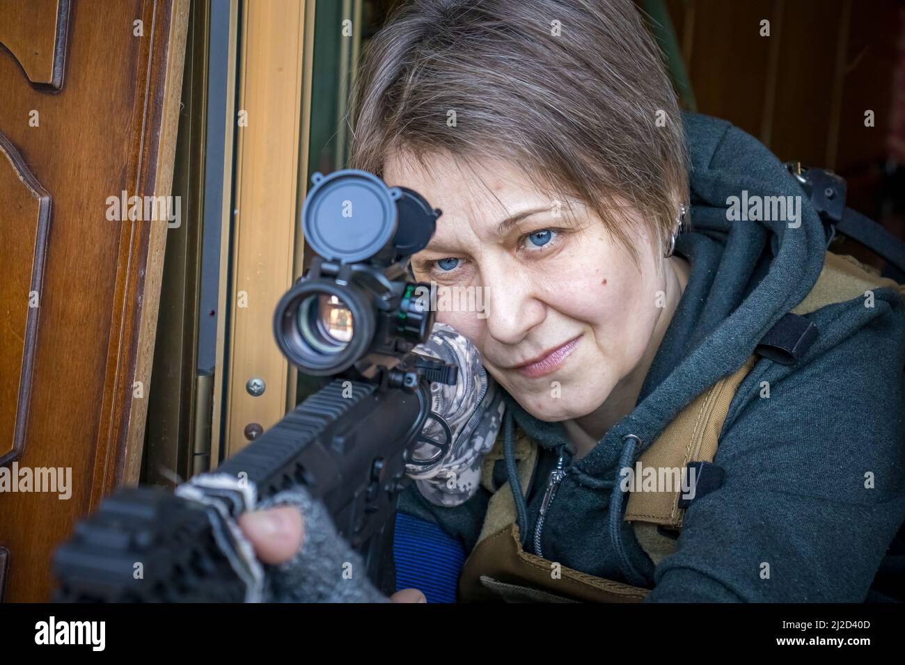 Echte ukrainische Zivilfrau mit Gewehr zur Verteidigung der Ukraine. Bürgerin mit Krieg und Waffen, die ihr Haus und die Stadt verteidigen. Stockfoto