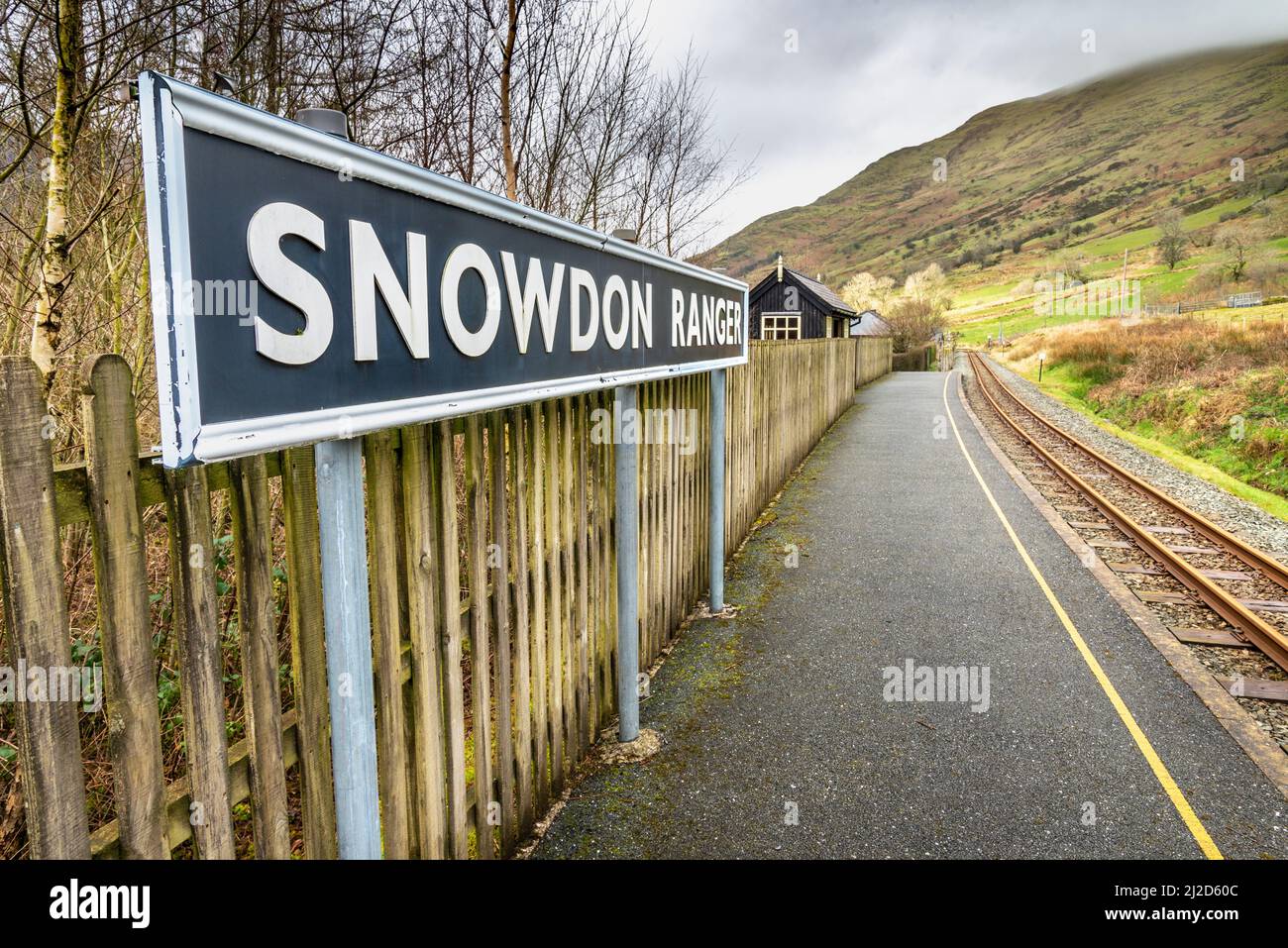 Snowdonia, Wales, UK-March 17. 2022:das Bahnsteigsschild, steht prominent an der kleinen, leeren, walisischen Bergbahnhalt, auf der Route hinauf zum Mount Stockfoto