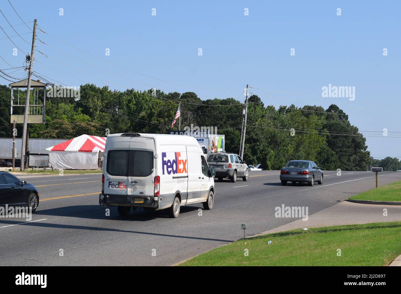 Kleiner FedEx Lieferwagen, der auf einer vierspurigen Straße in Rockport, AR, fährt; nach rechts Stockfoto