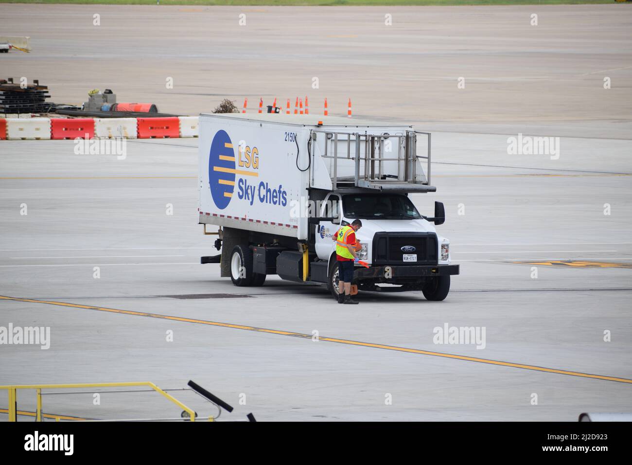 Dallas-Ft. Flughafen Worth: Ein Mitarbeiter von LSG Sky Chefs, der vor seinem Lastwagen auf dem Asphalt des internationalen Terminals des DFW-Flughafens steht Stockfoto