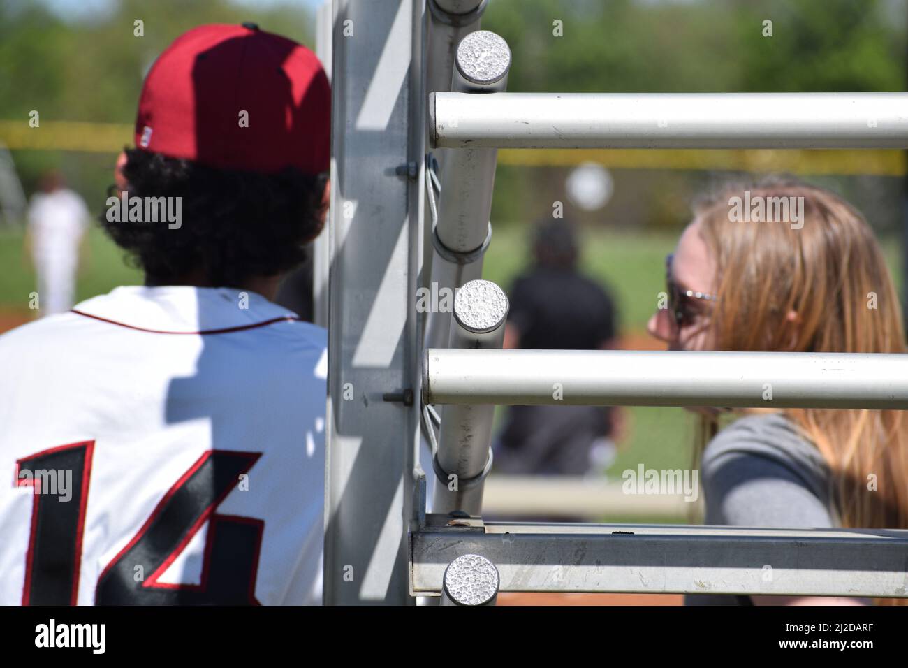 College-Baseballspieler am Dallas Christian College, Nummer 14, steht neben seiner Freundin, die auf der Tribüne sitzt Stockfoto