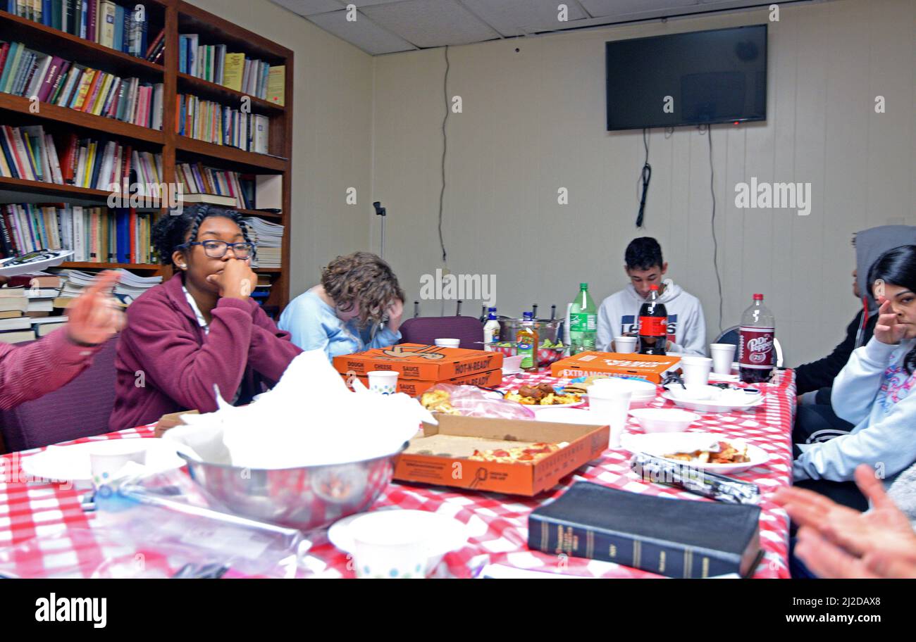 Mitglieder einer College Age + Bible Klasse teilen sich eine Mahlzeit und ein Bibelstudium Stockfoto