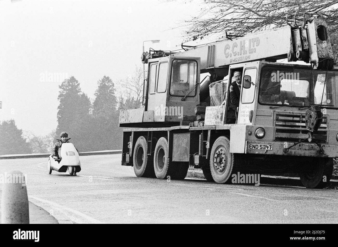 Das neue Elektrofahrzeug der 14-jährige Joe Paine aus London probiert das neue Elektrofahrzeug von Sir Clive Sinclair aus. Hier fährt er an der Seite eines Lastwagens, um die schiere Kleinheit des Fahrzeugs aus dem Jahr C5 zu zeigen. Bild aufgenommen am 10.. Januar 1985 Stockfoto