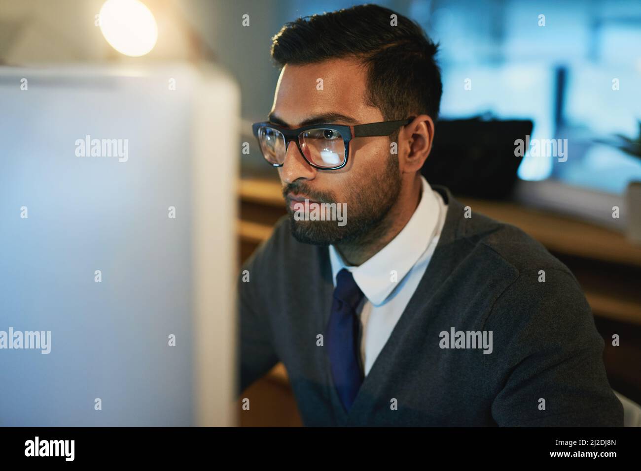 Die Kerze an beiden Enden verbrennen. Ausgeschnittene Aufnahme eines jungen Geschäftsmanns, der spät im Büro arbeitet. Stockfoto