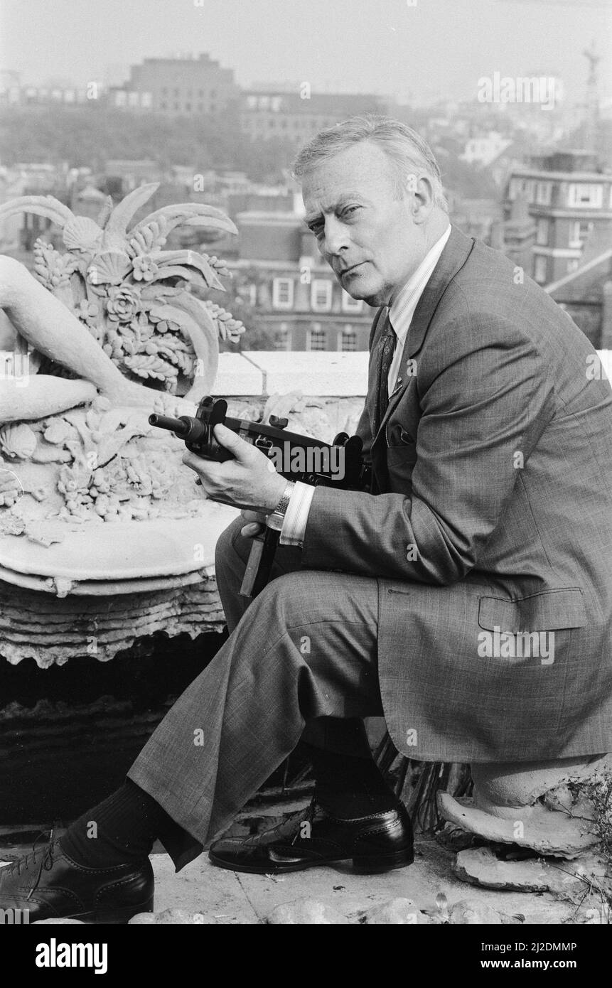 Der britische Schauspieler Edward Woodward, der in der amerikanischen Fernsehserie The Equalizer den Ex-Agenten Robert McCall spielt, posiert in London mit einem Maschinengewehr, um die Serie zu promoten.25.. Oktober 1986. Stockfoto