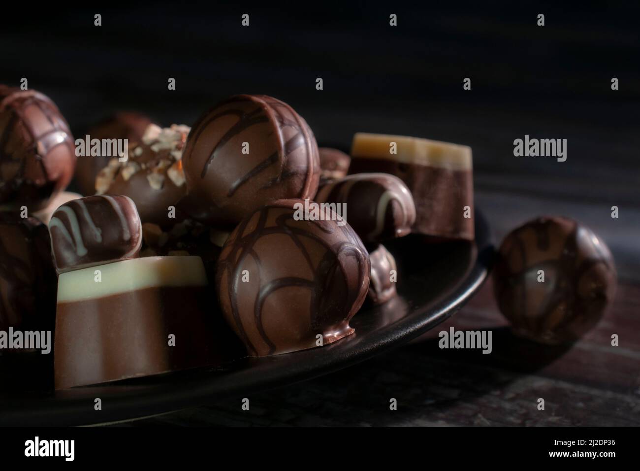 Pralinen auf einem dunklen Teller auf schwarzem Hintergrund, Concep von süßen Dessert Food Makrofotografie Stockfoto
