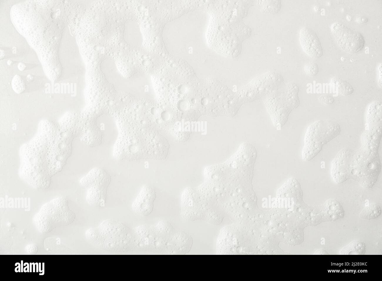 Schaumstoff auf weißem Grund mit Spuren von Seife und Duschwasser. Draufsicht. Horizontale Zusammensetzung. Stockfoto