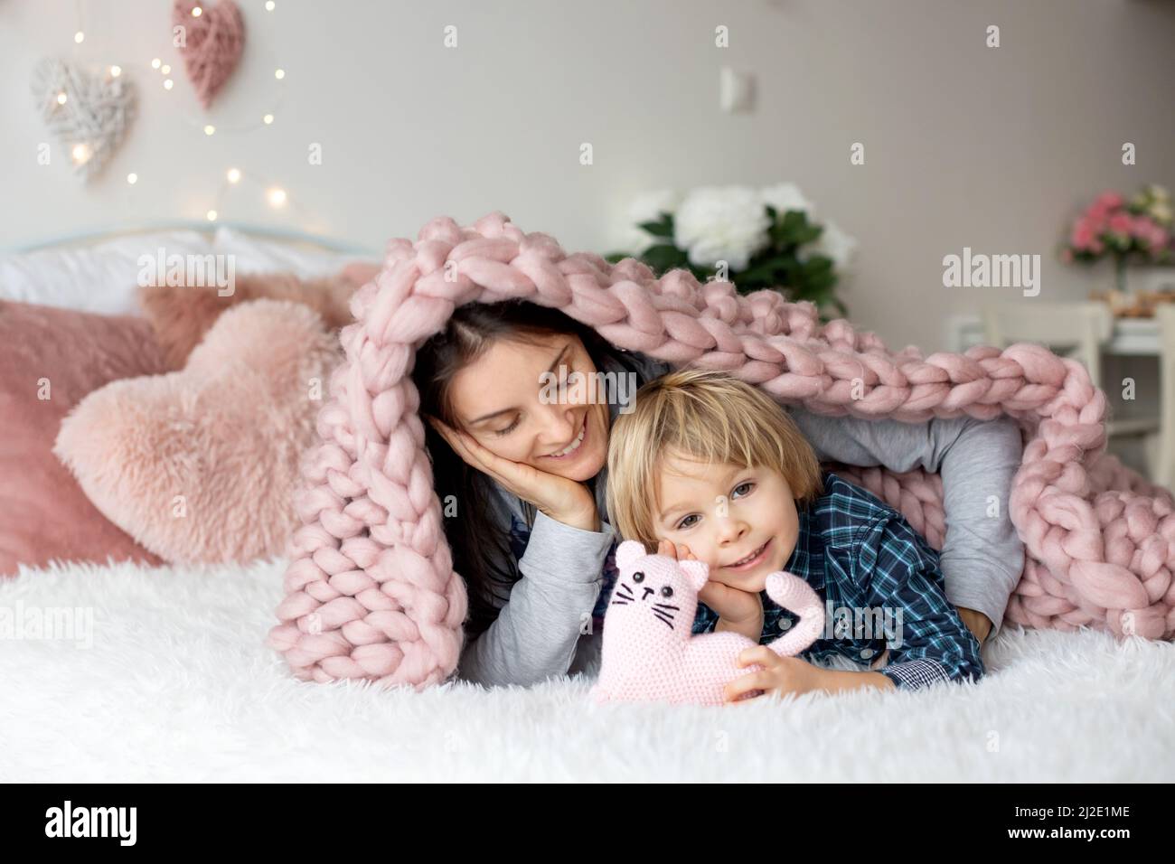Schöne blonde Junge und Mutter, im Bett liegend, versteckt unter Decke, genießen Familie Zeit zusammen Stockfoto